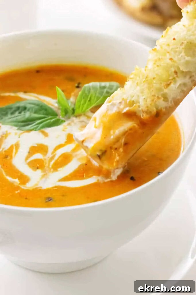 Dipping bread into a bowl of roasted tomato soup.