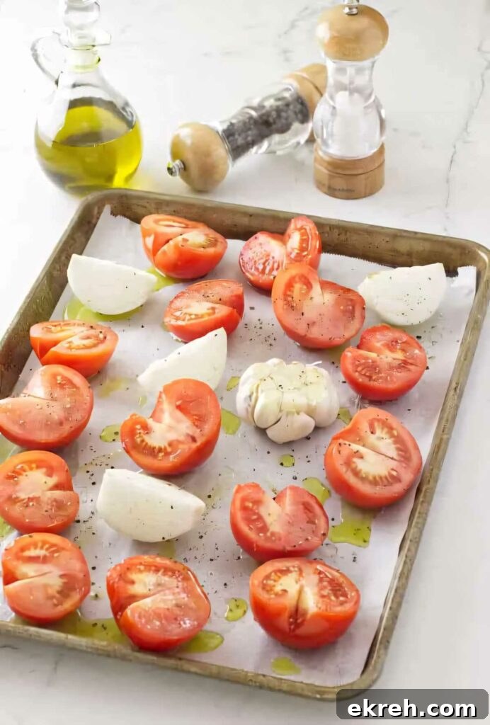 Spreading sliced tomatoes, onions, and garlic out on a baking sheet to roast for soup.