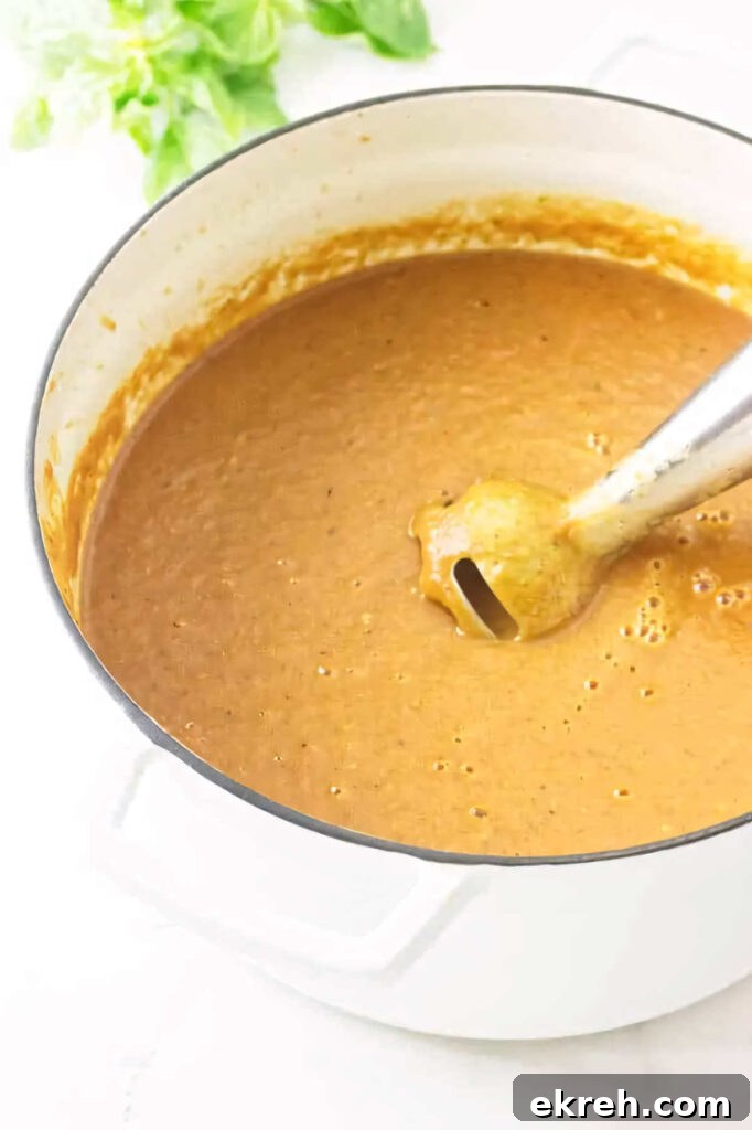 Using an immersion blender to puree soup in a pot.