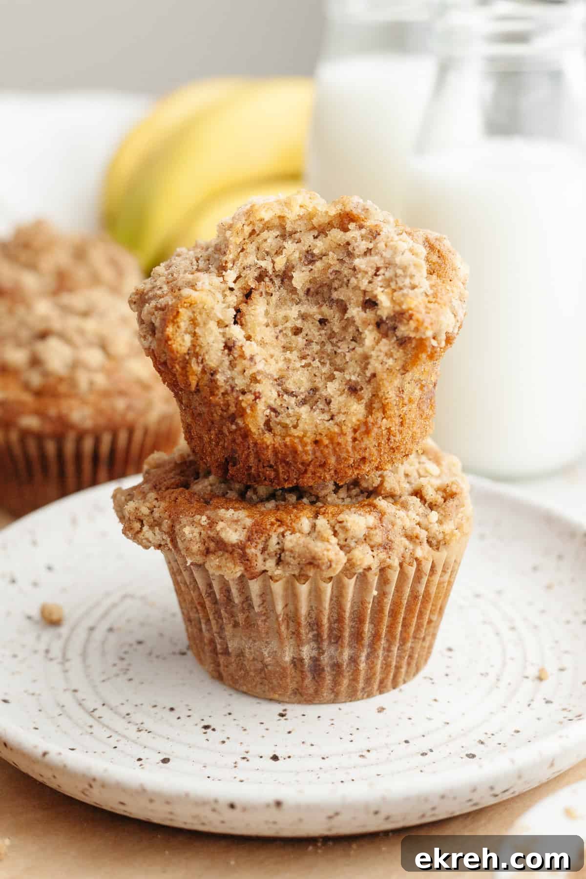 A stack of two banana coffee cake muffins, one has a bite taken out of it.