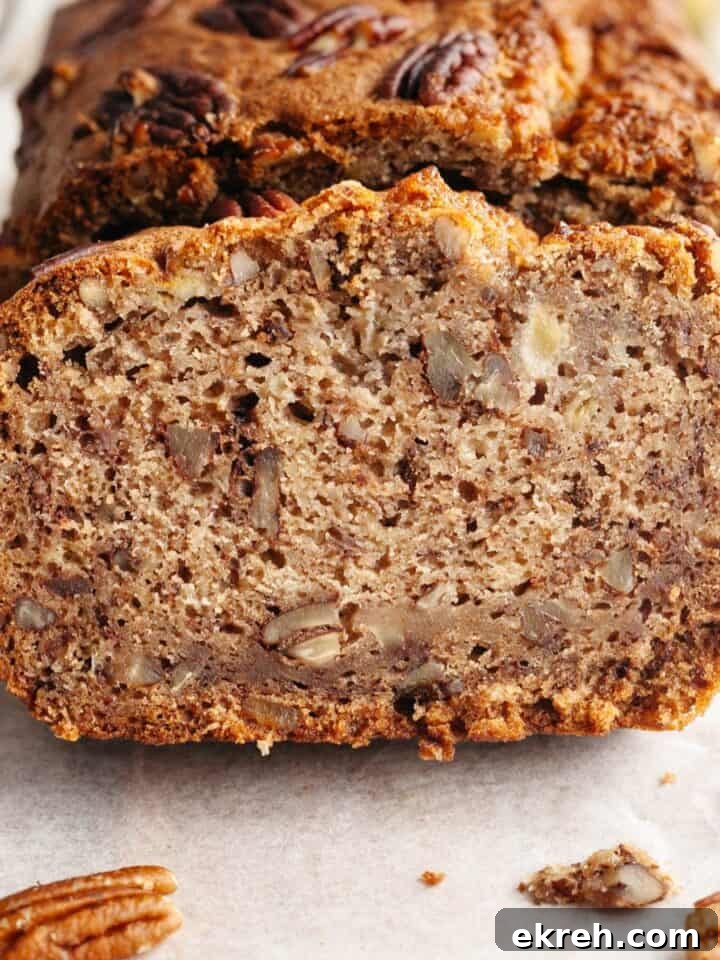 A close up of a slice of pecan banana bread on parchment paper.