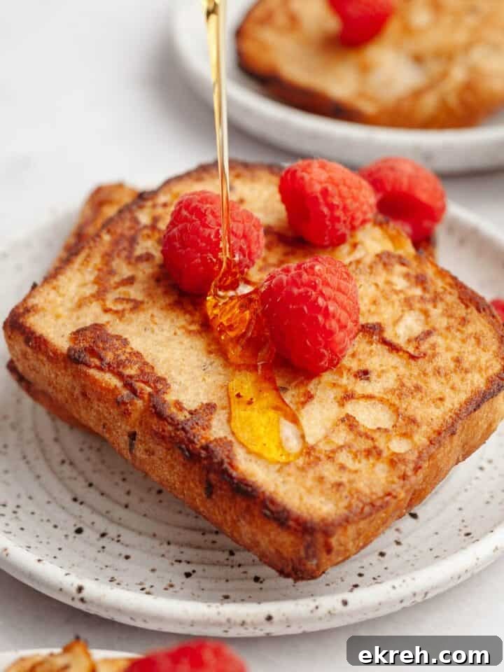 Two slices of buttermilk french toast on a small plate with raspberries.