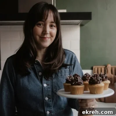 Ella from Alpine Ella is holding a cake stand with cupcakes on it.