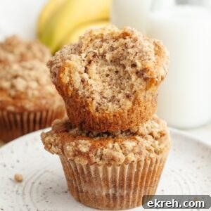 A stack of two banana coffee cake muffins, one has a bite taken out of it.
