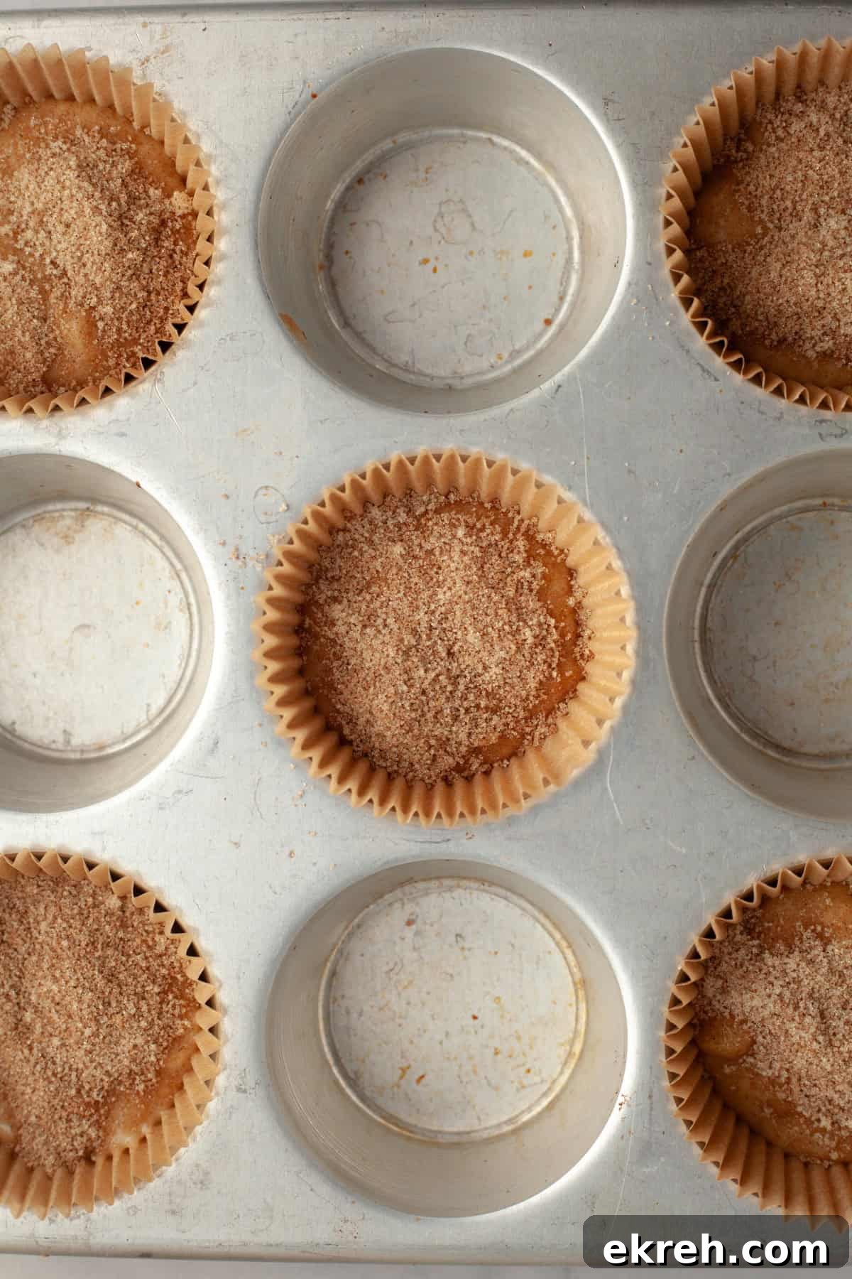 A muffin pan with unbaked banana muffins covered in cinnamon sugar.
