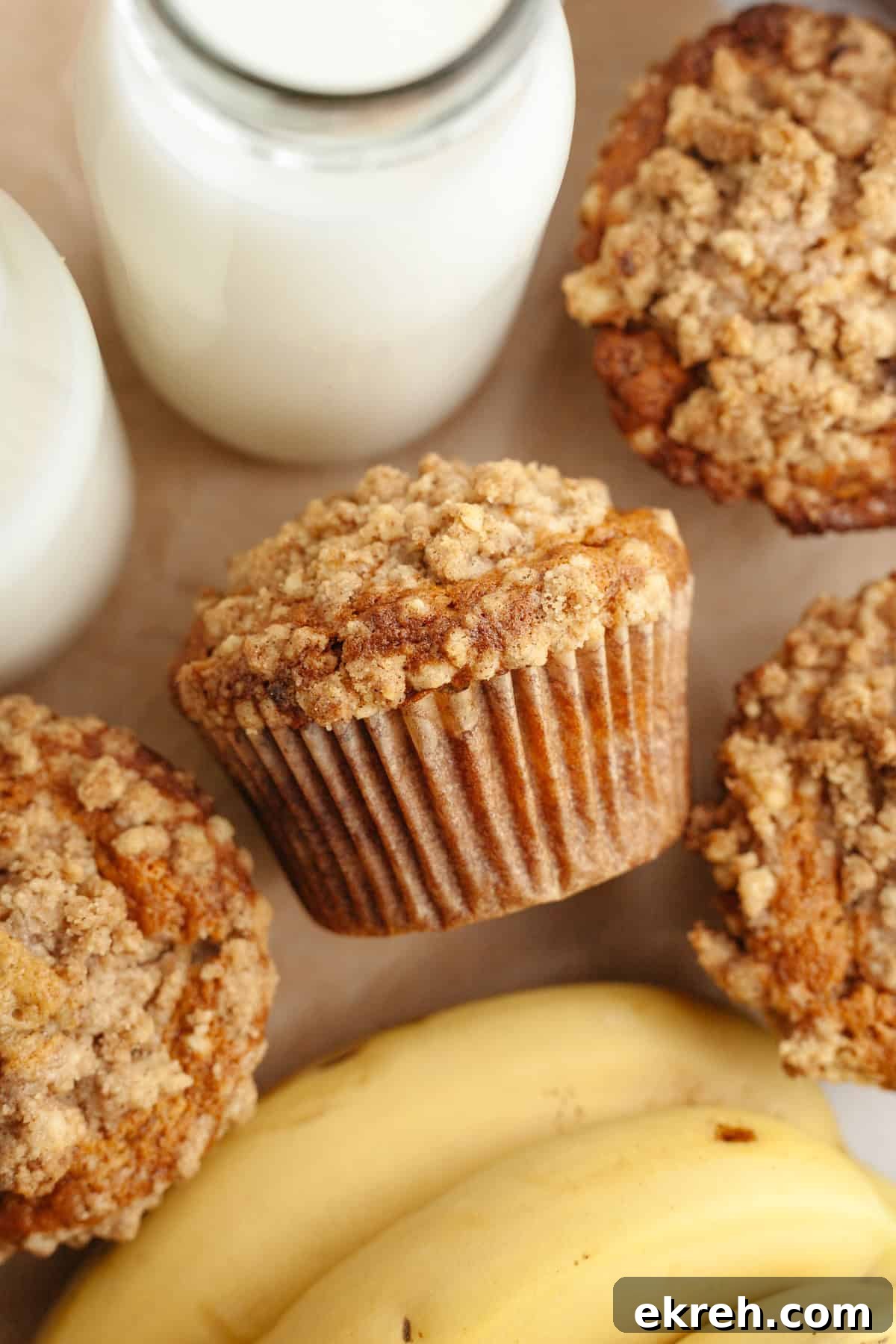 Banana coffee cake muffins with streusel topping on parchment paper.