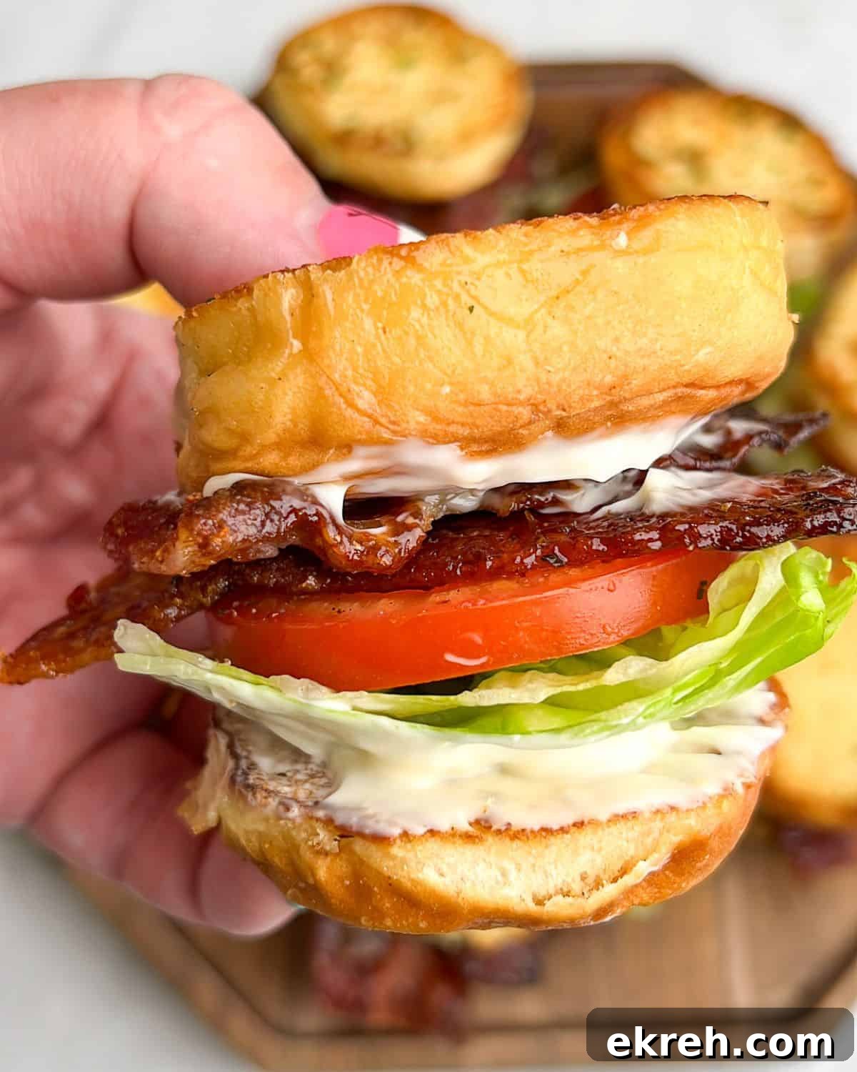 Candied Bacon BLT Sliders with Maple Glaze 2 candied bacon blt slider sandwiches being held in hand