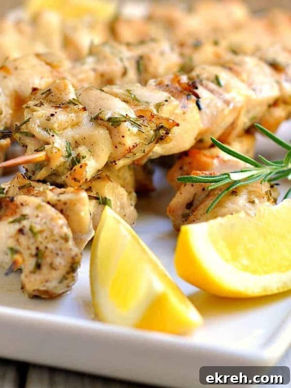 Rosemary garlic chicken kabobs on a white serving tray with fresh lemon.