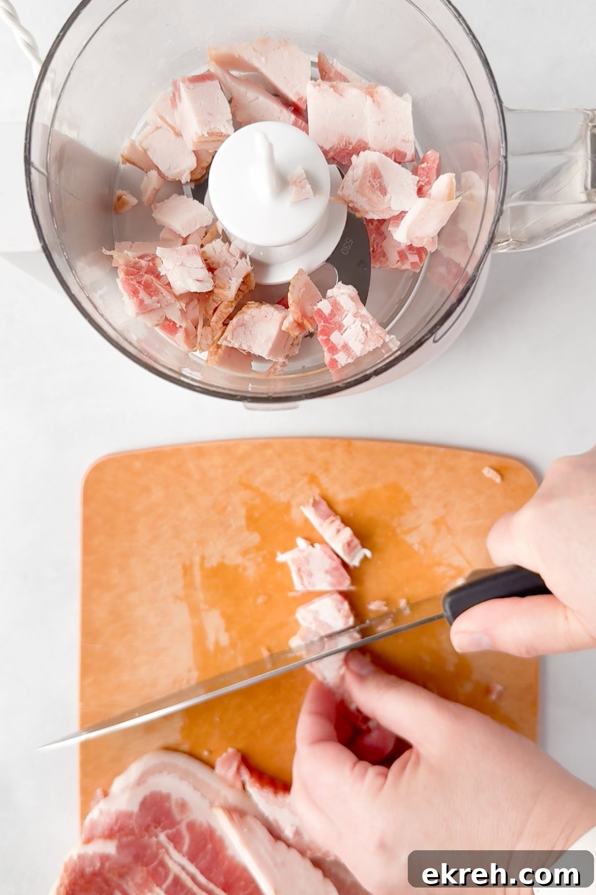 Juicy Grilled Bacon Cheeseburgers with Beef and Pork Patties 5 A person slicing raw bacon on a cutting board with a knife, with chopped pieces of bacon already placed in a food processor nearby.
