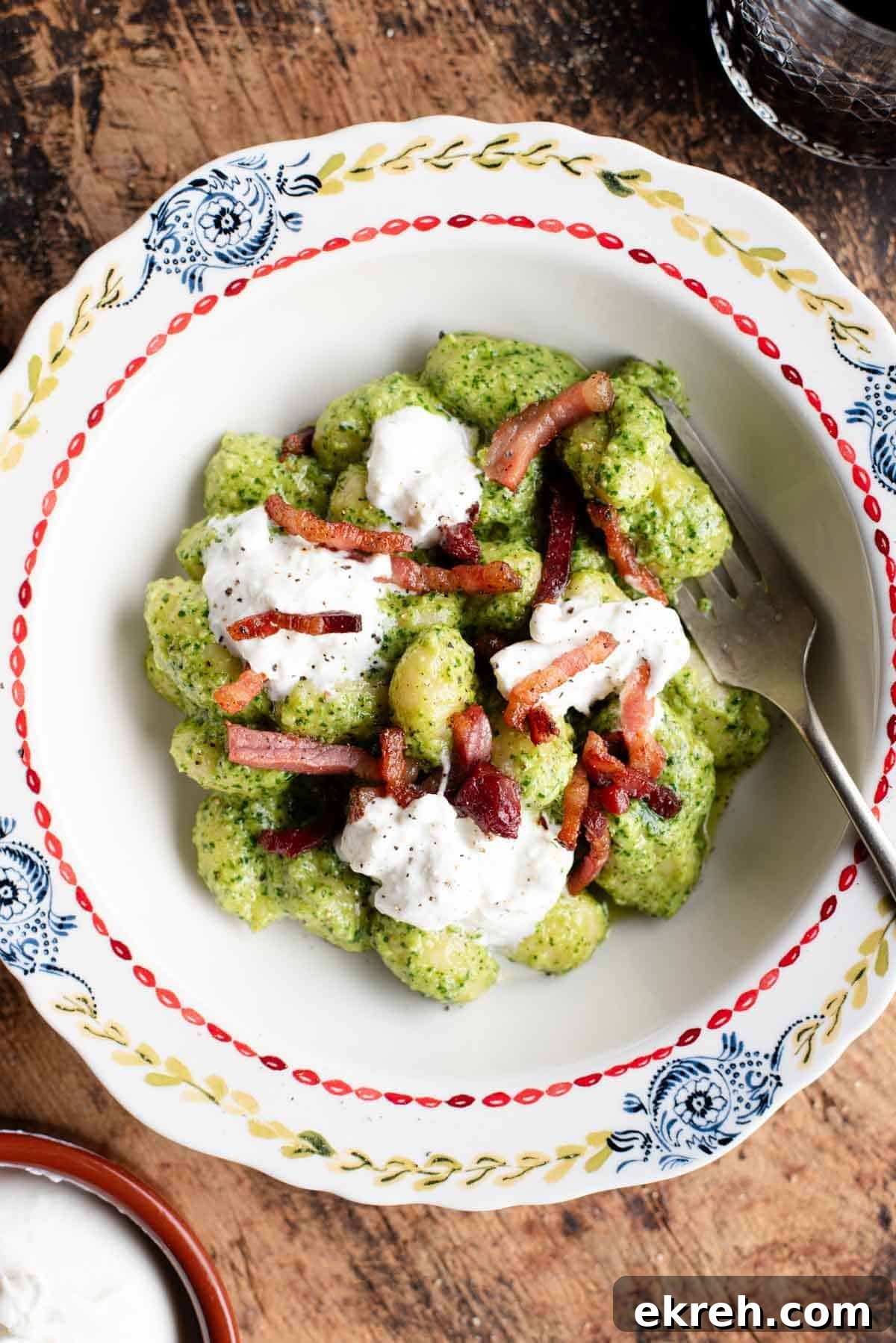 Arugula Pesto Gnocchi with Creamy Burrata and Crispy Pancetta 2 An overhead shot of arugula pesto gnocchi in a bowl topped with crispy pancetta and burrata.