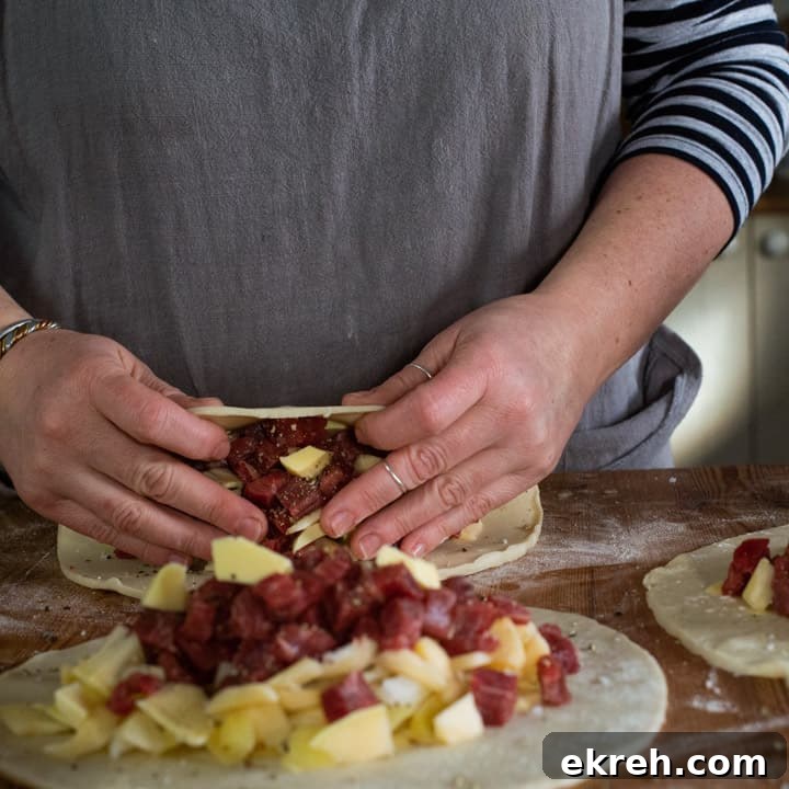 How to Make a Traditional Cornish Pasty (Authentic Recipe) 11 womans hands folding pastry over pasty fillings read to crimp