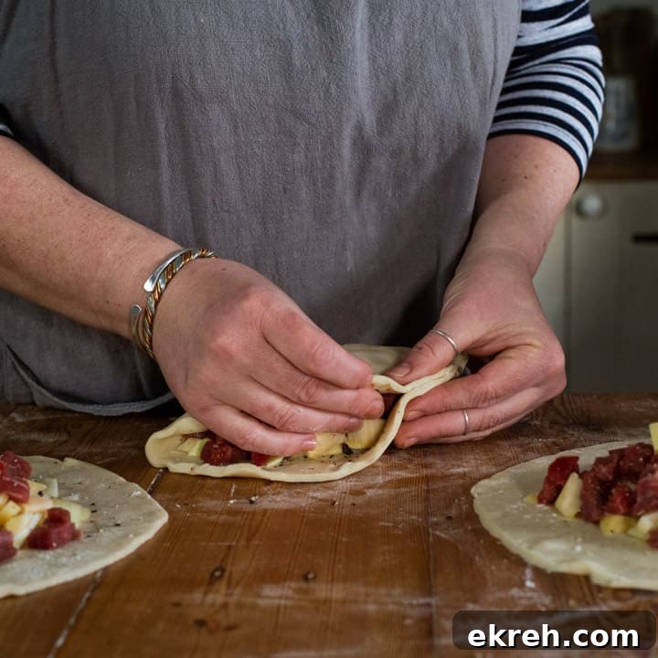 How to Make a Traditional Cornish Pasty (Authentic Recipe) 13 womans hands making a steak pasty on a wooden kitchen counter