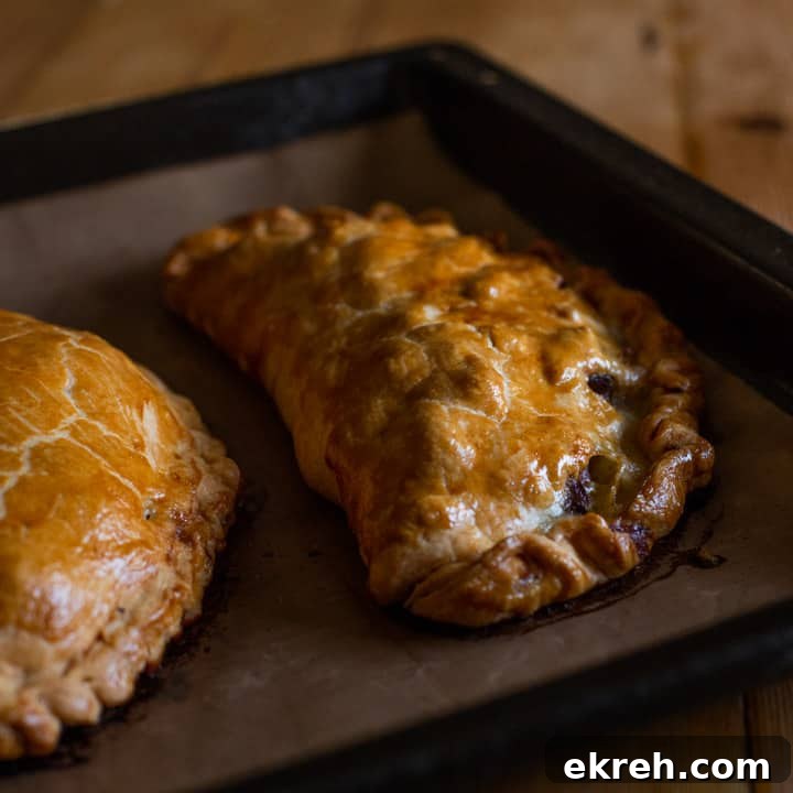 How to Make a Traditional Cornish Pasty (Authentic Recipe) 16 golden brown baked pasty's on brown baking paper on a black tray