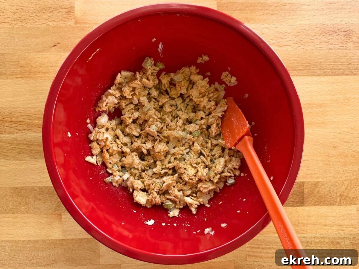 Binder ingredients with crushed saltines in a red bowl with a spatula.