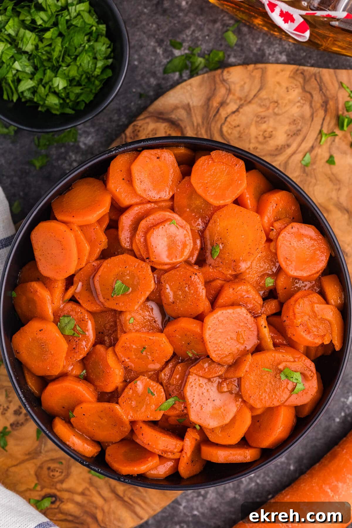 Oven-Roasted Maple-Glazed Carrots Recipe 2 A bowl of Maple Glazed Carrots on a wooden surface.