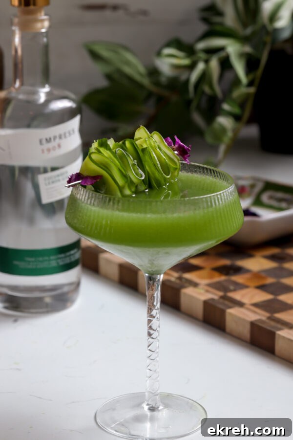Cucumber martini garnished with sliced cucumber and edible flowers.