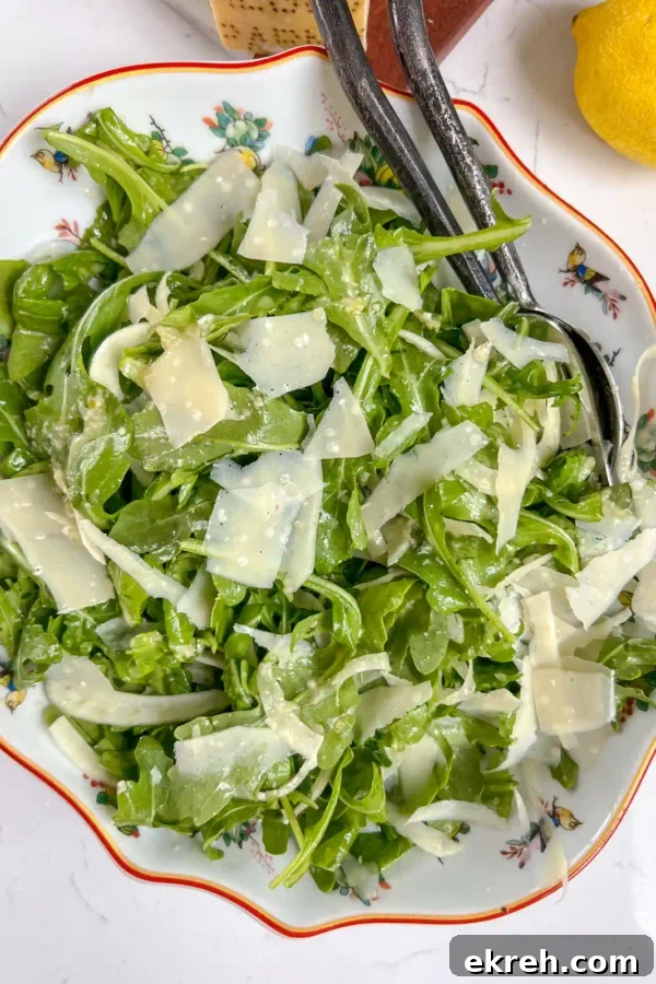 A bowl of arugula fennel salad tossed with honey dijon and shaved parmesan.