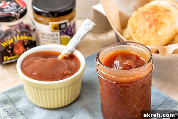 Honey Apple Butter Recipe and 10 Ways to Use It 3 A jar and ramekin filled with a homemade honey apple butter recipe with biscuits in the background.