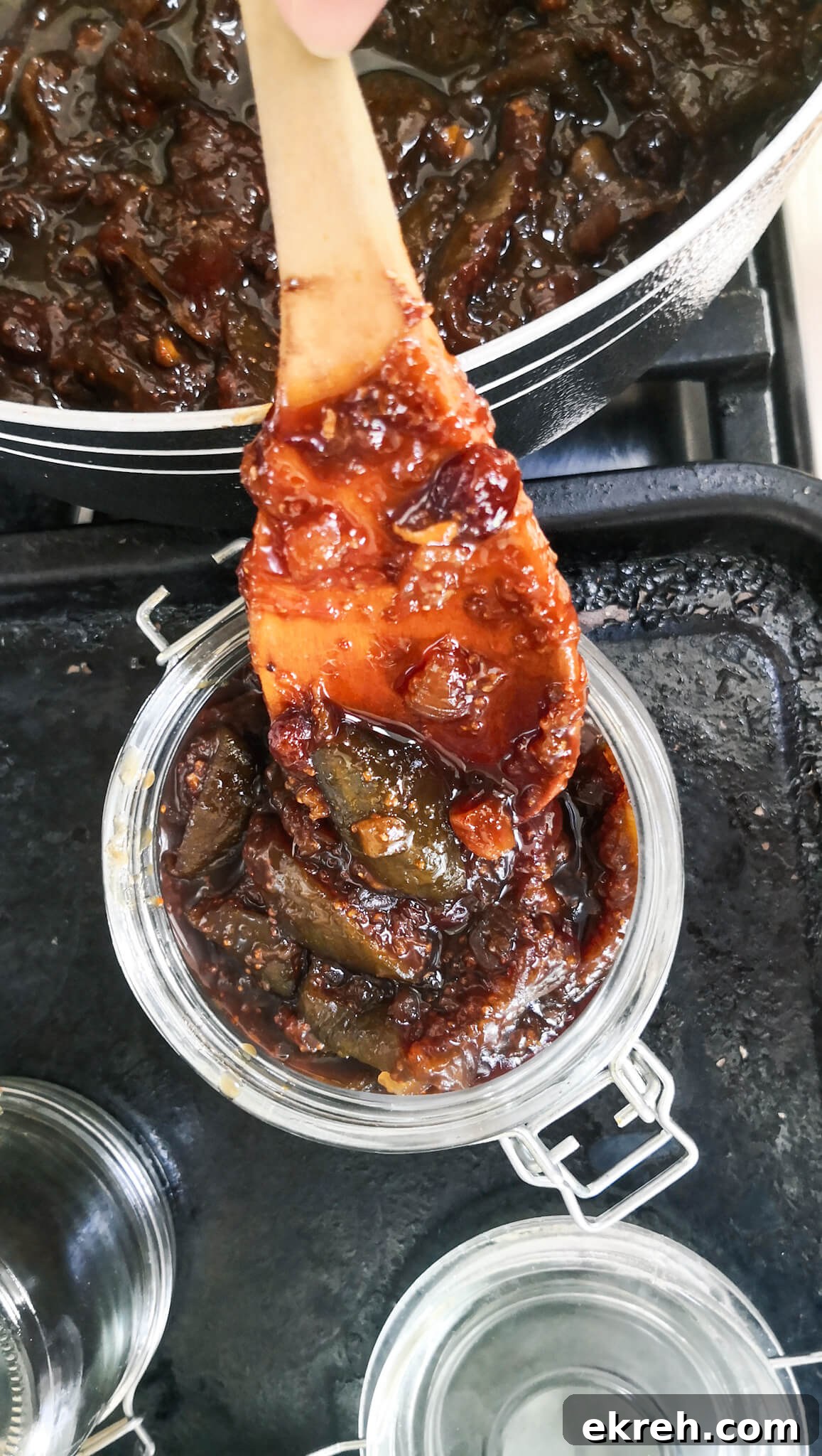 Large wooden spoon transferring chutney into sterilised jars.