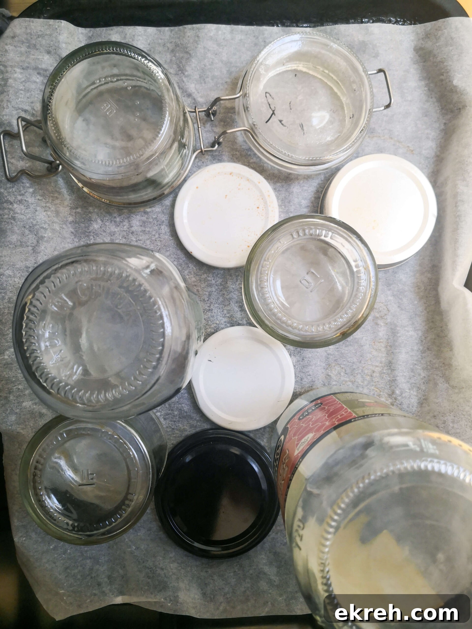Glass jars standing upside down on a lined oven tray.
