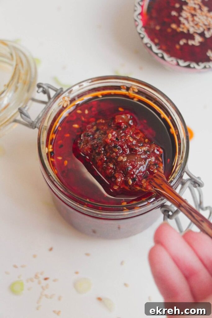 Hand holding a wooden spoon with chilli oil on it.