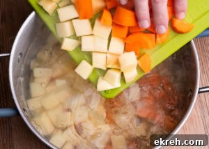 Placing chopped carrot and swede into a large pot of boiling water