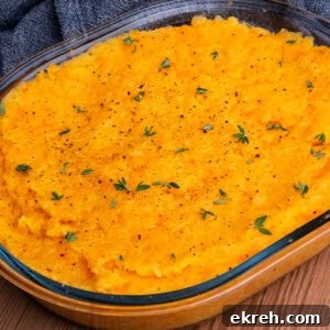 Carrot and Swede Mash in a glass dish with pepper and fresh thyme sprinkled on top