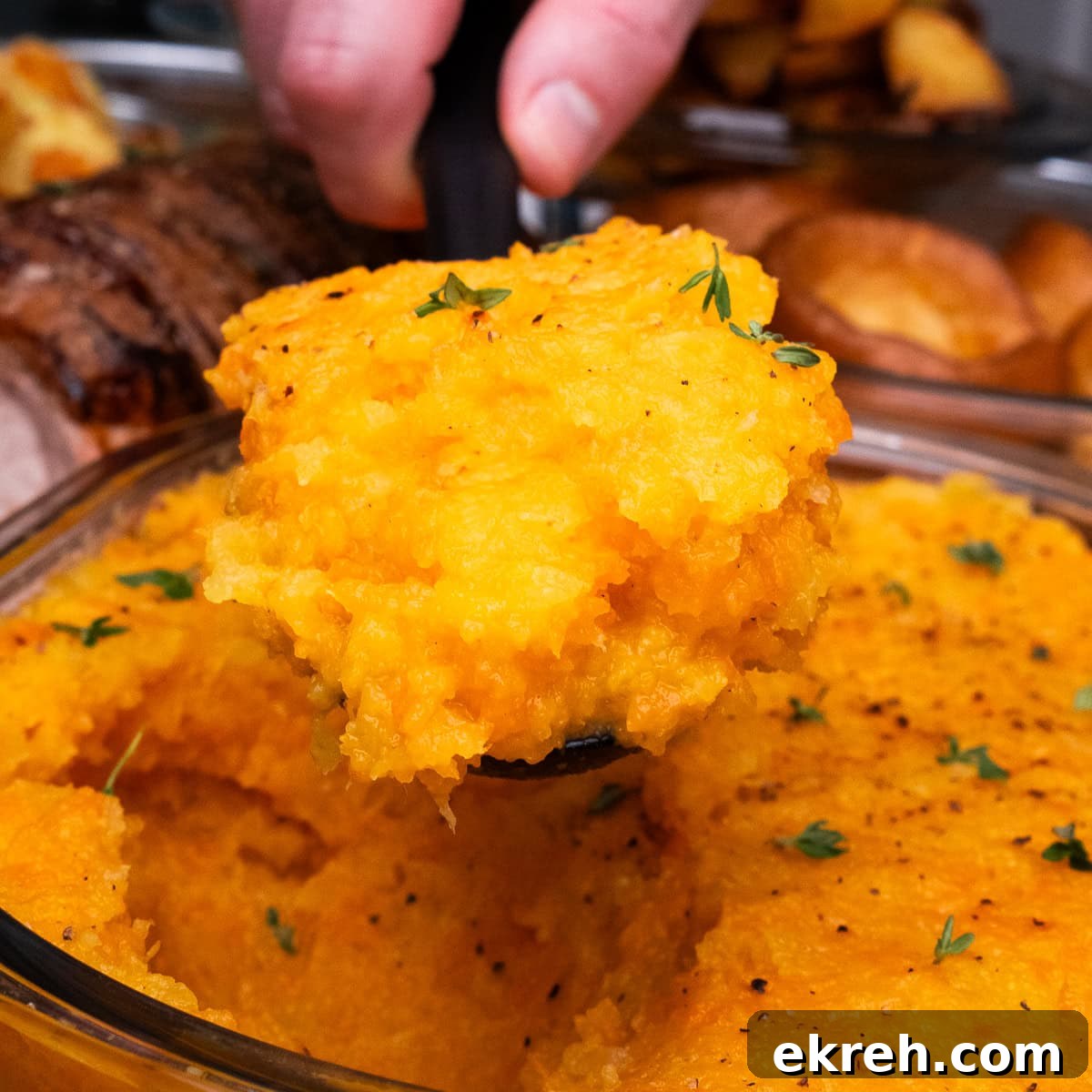 Swede and carrot Mash being scooped up with a spoon to serve as a roast dinner side dish