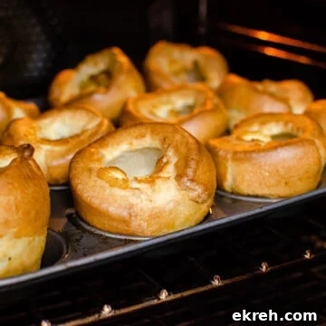 Flawless Yorkshire Puddings cooked in a cupcake tin on a metal rack in the oven