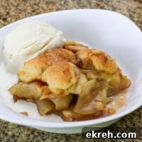 apple cobbler in a serving dish with ice cream on the side.