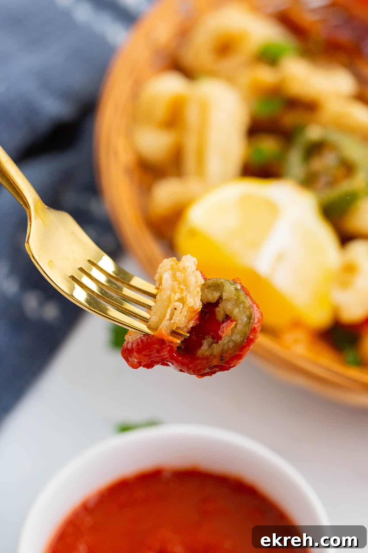 Calamari rings on fork dipped in marinara sauce.