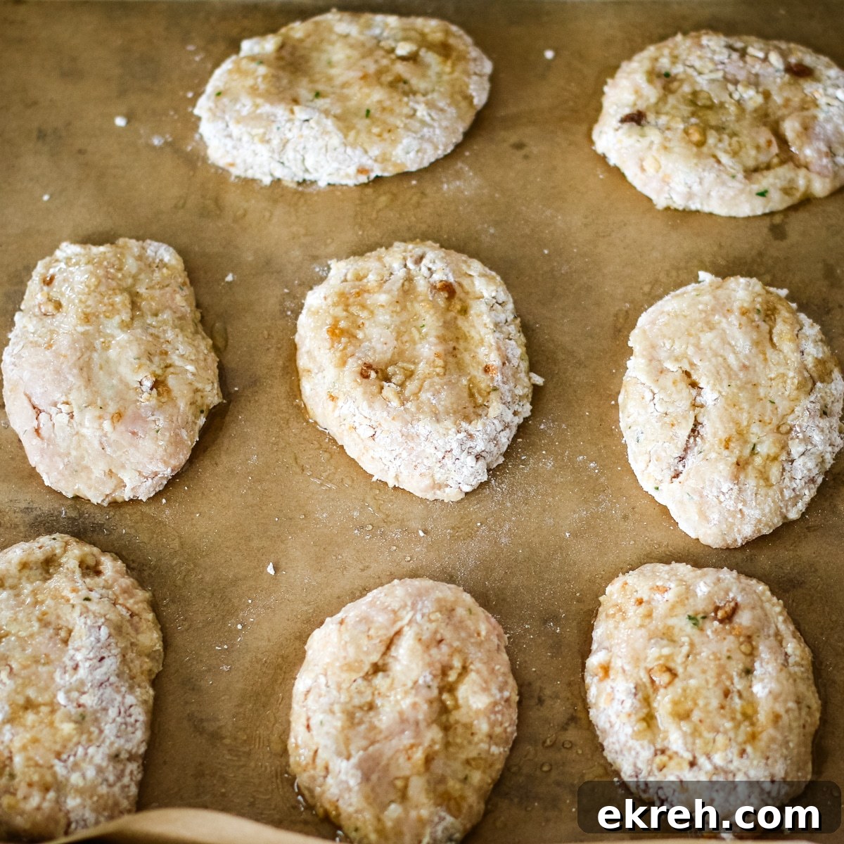uncooked, flattened chicken kotleti resting on a sheet of brown parchment paper.