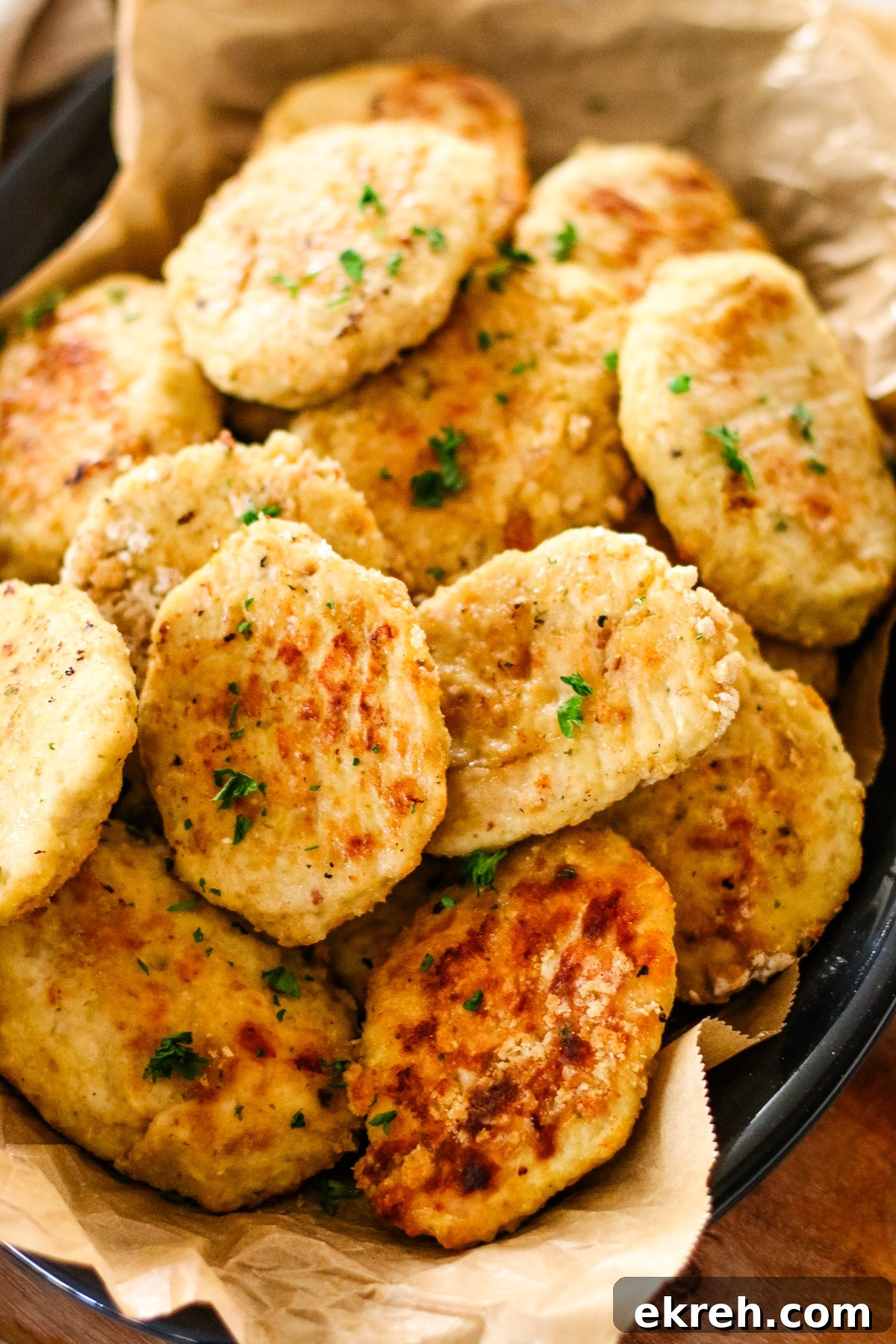 close-up shot of a platter piled high with golden-brown chicken kotleti, garnished with chopped parsley.