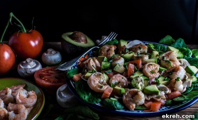 spinach salad with shrimp and a smoky sweet dressing on a table with extra ingredients and a fork