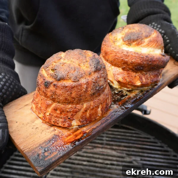 Grilled Jalapeno Popper Salmon Pinwheels on a cedar plank over a charcoal grill.