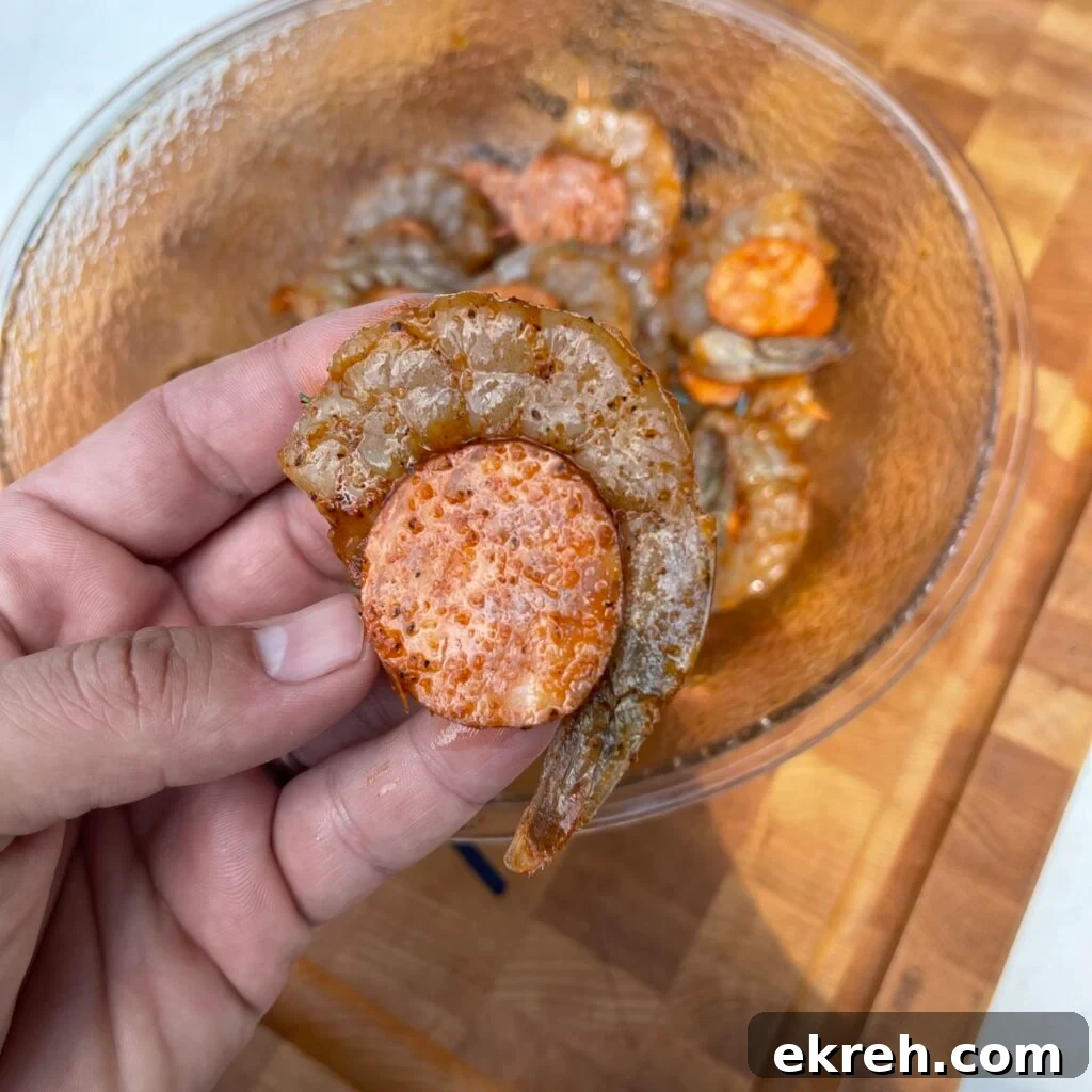 Bowl with cut sausage medallions and raw shrimp ready to season