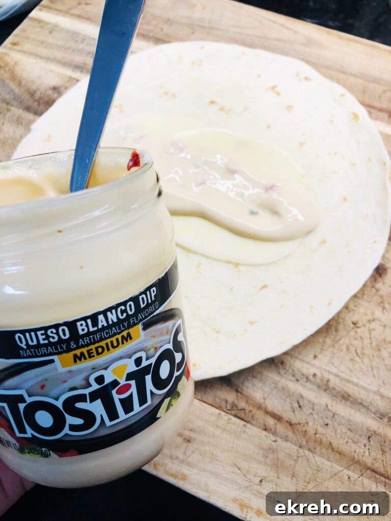 Air Fryer Philly Chicken Burritos Recipe 4 putting queso on the burrito