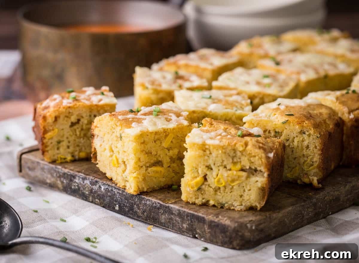 Cheddar and Chive Skillet Cornbread Recipe 8 Sliced gluten-free cheddar chive cornbread on a serving board. Next to saucepan of hot soup, ready for serving.
