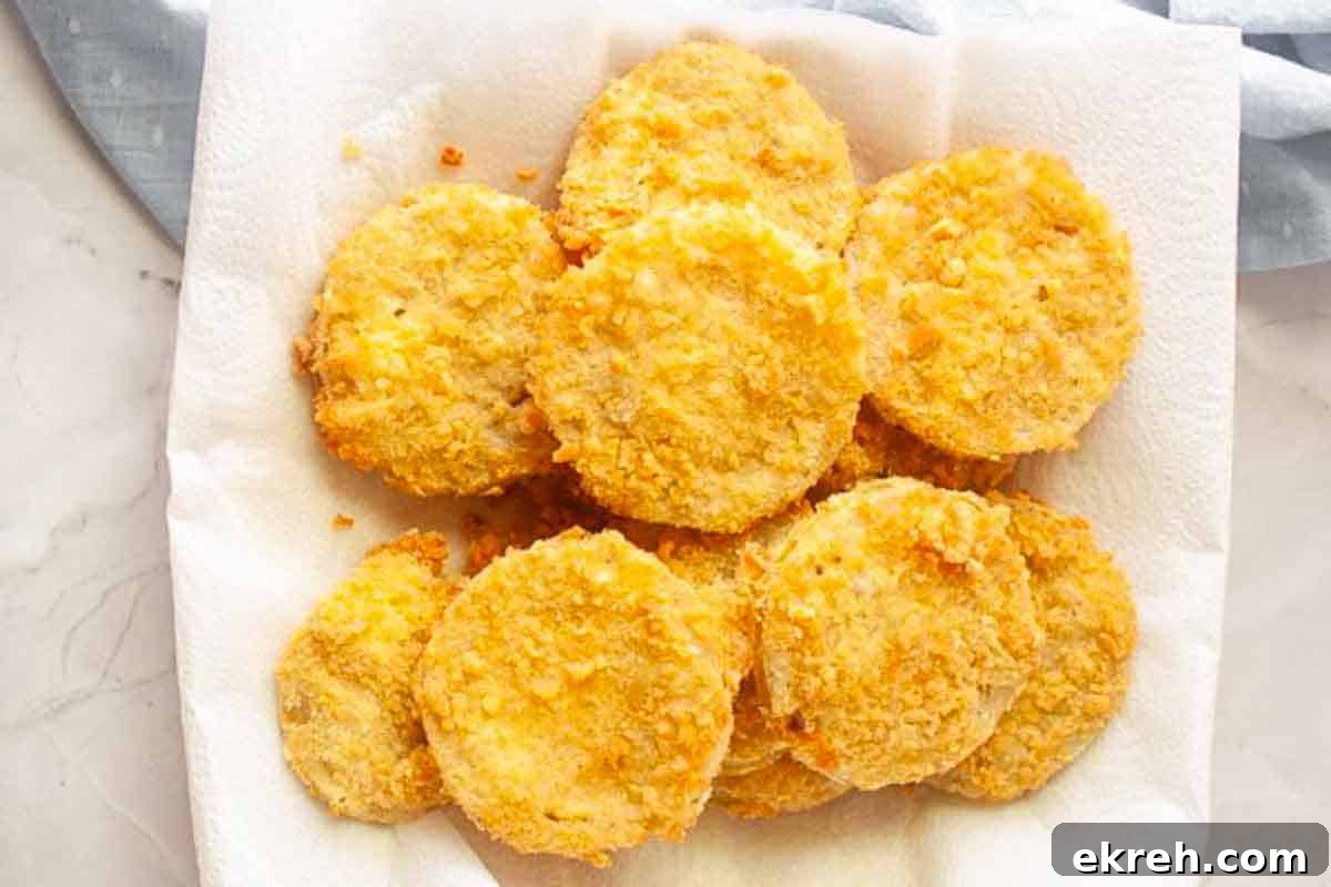 A plate of golden-brown fried green tomato slices on a paper towel, seen from above.