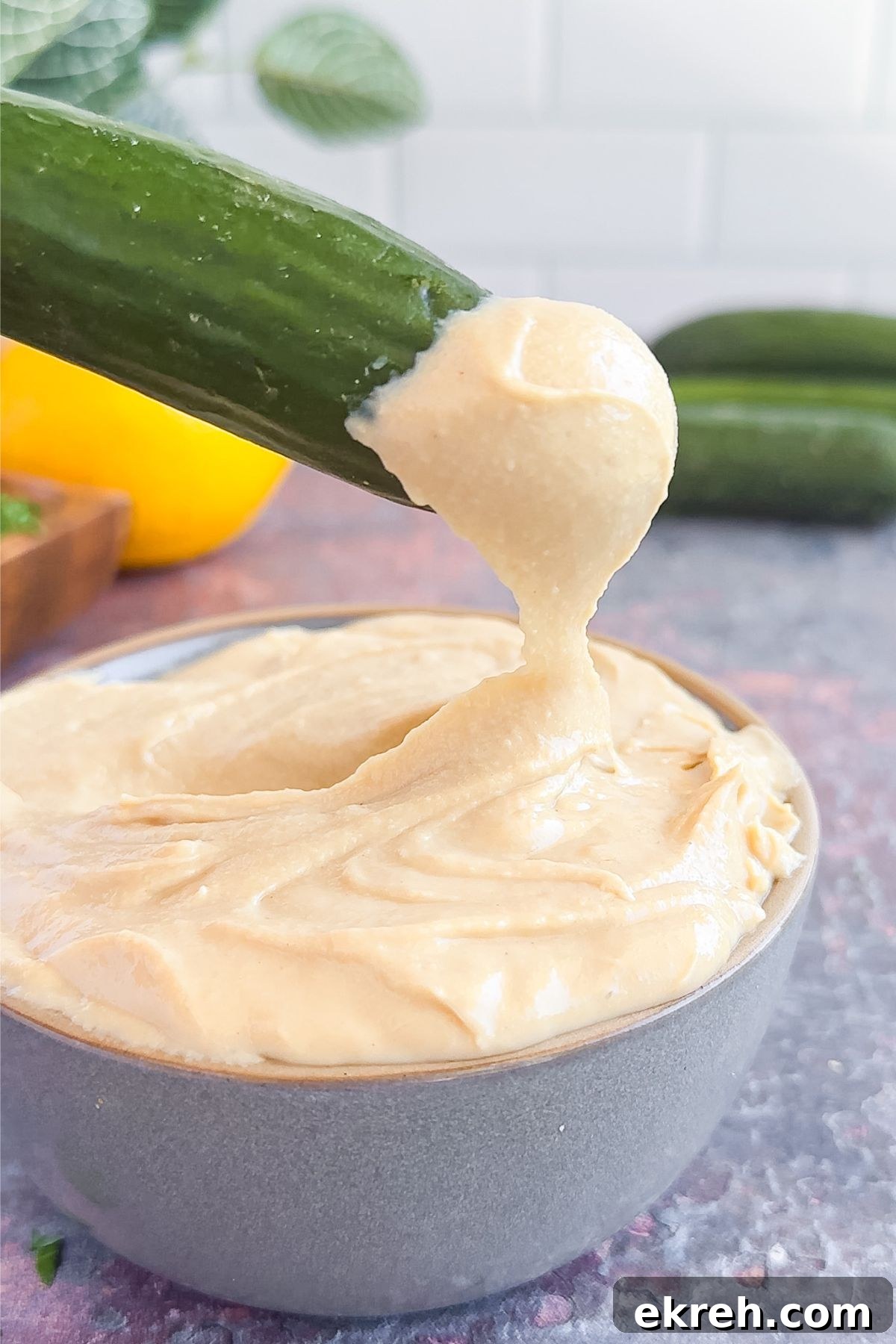Tahini Sauce Recipe: Creamy Salad Dressing and Dips 7 Dipping a cucumber into tahini sauce.