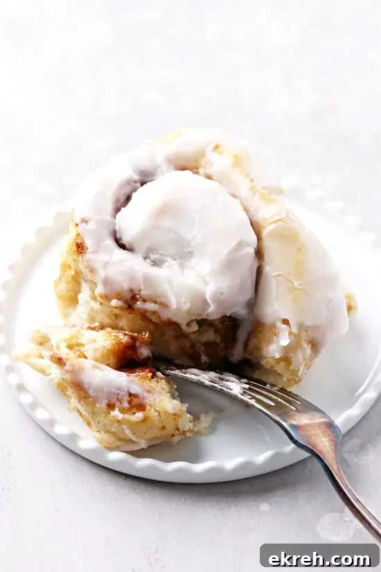 Dairy-Free Cinnamon Rolls Recipe: Soft, Gooey, Fluffy 6 A Non Dairy Cinnamon Bun on a plate with a fork.