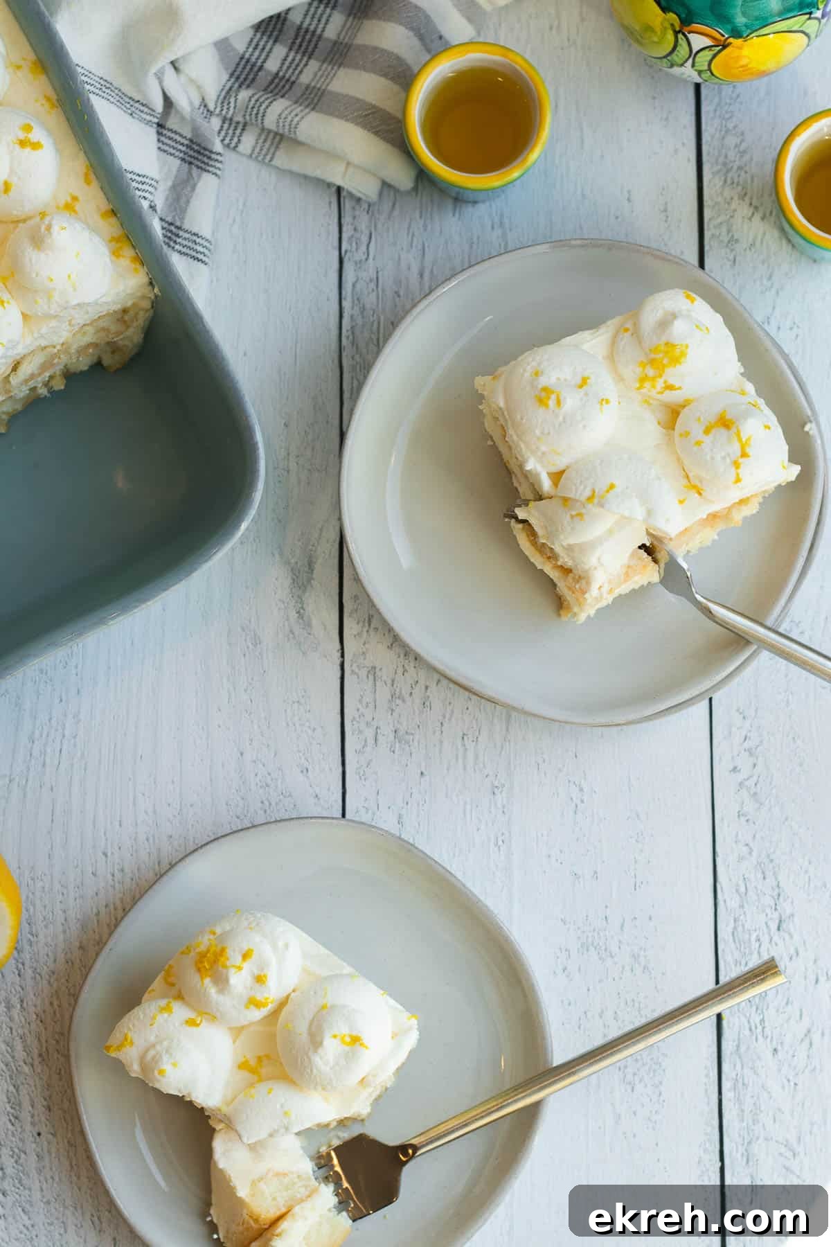 Limoncello Tiramisu Recipe with Zesty Lemon Mascarpone 3 limoncello tiramisu slices on cream colored plates with blue baking dish and cups of limoncello