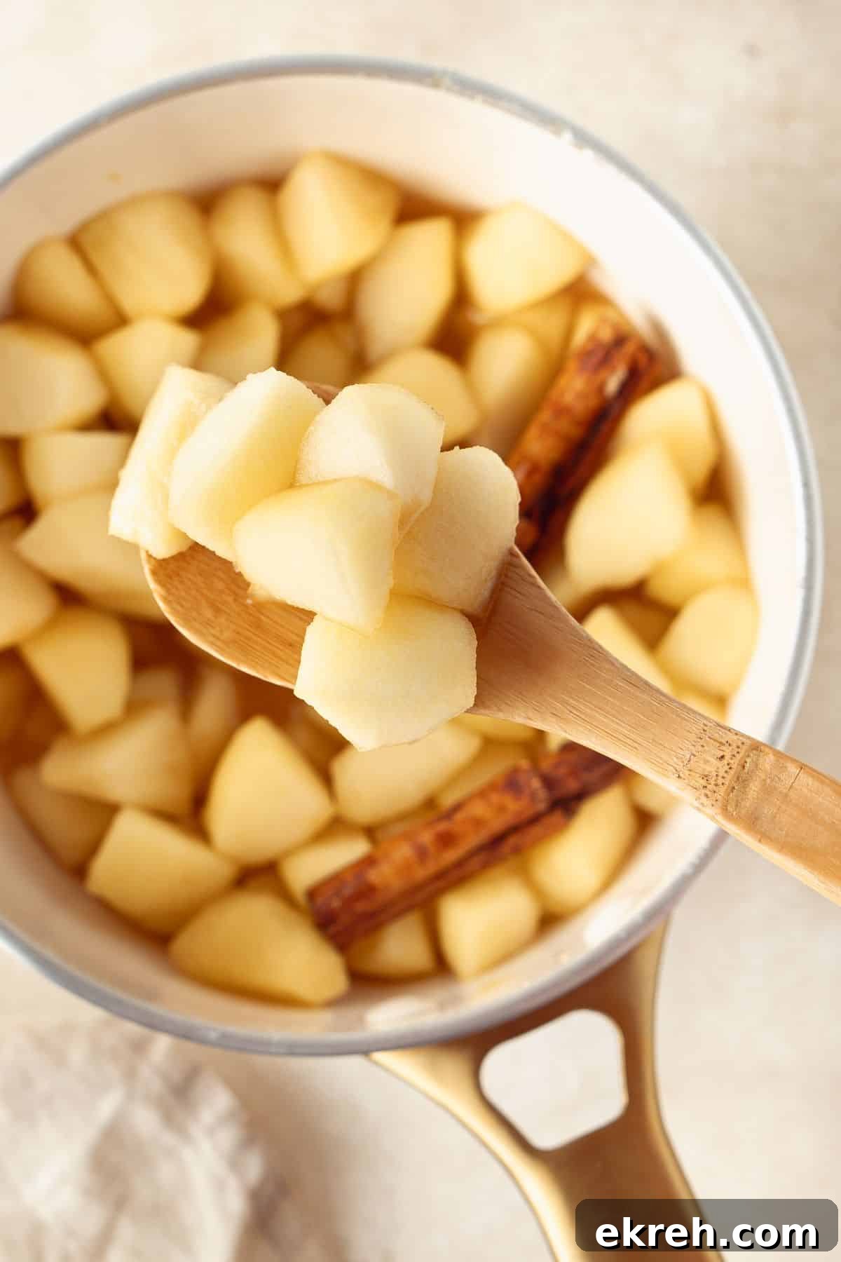 Saucepan of Stewed Apples, with a wooden spoon lifting some up out of the pan.