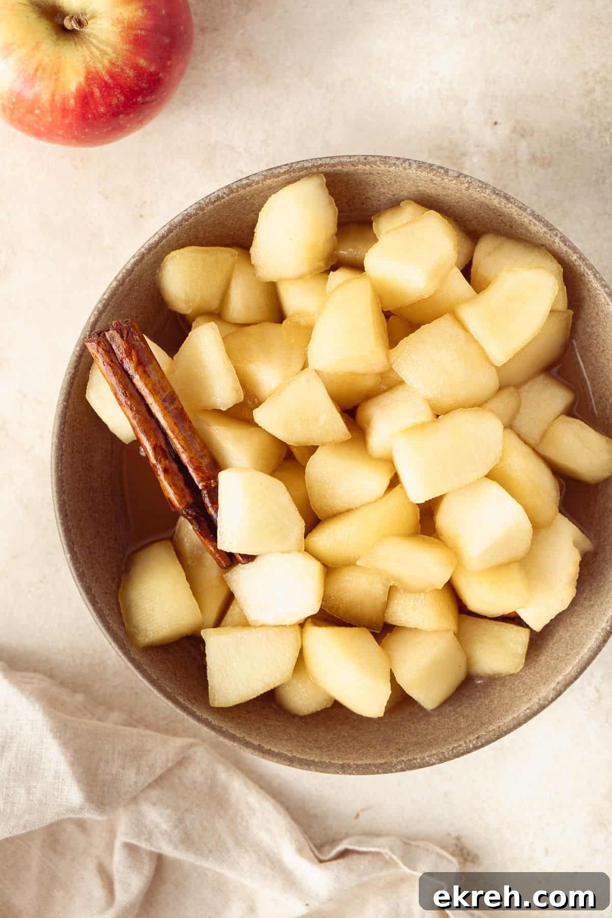 Small round dish of Stewed Apples, with a cinnamon stick sitting in the bowl.