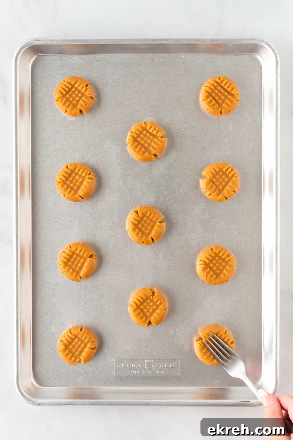using a fork to criss cross the peanut butter cookies