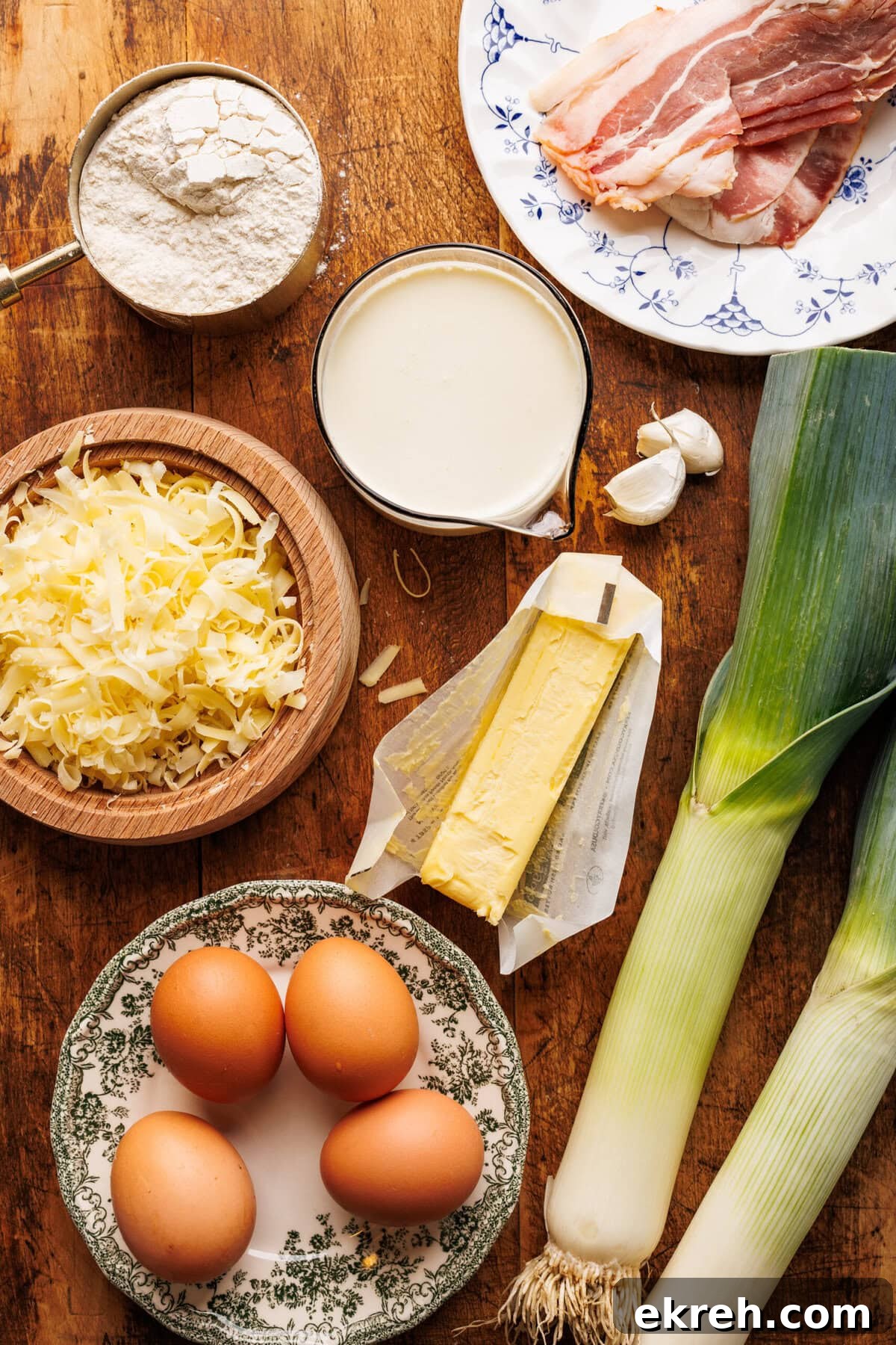 Ingredients for quiche Lorraine arranged on a brown wooden board. 
