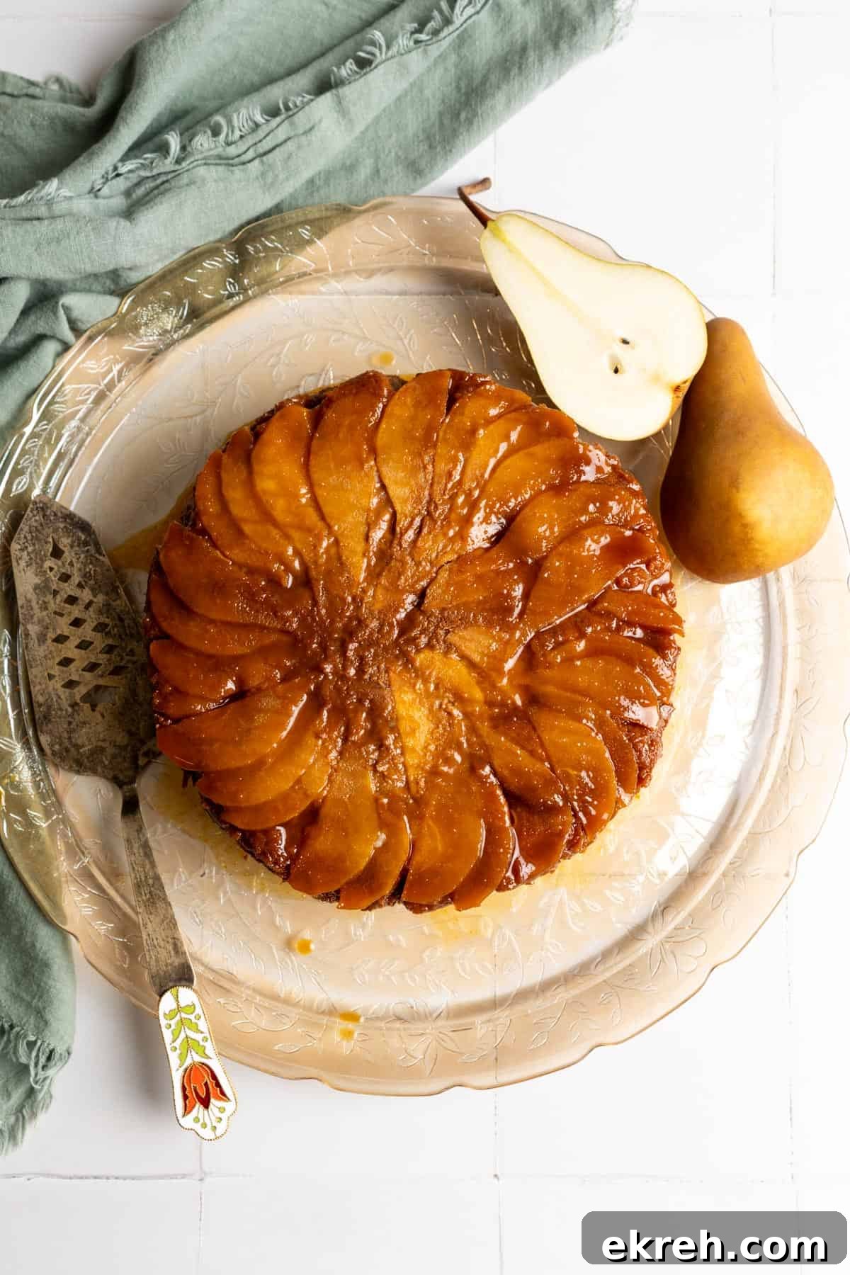 Bread pudding topped with sliced pear and miso caramel sauce on a glass serving plate.