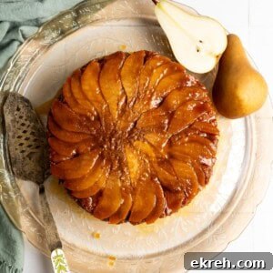 Bread pudding topped with sliced pear and miso caramel sauce on a glass serving plate.