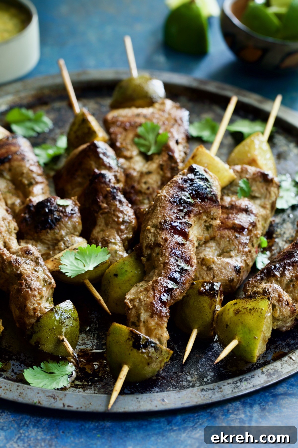 Grilled Citrus Mojo Pork Tenderloin Skewers 3 Mojo-Marinated Pork Skewers on metal tray.