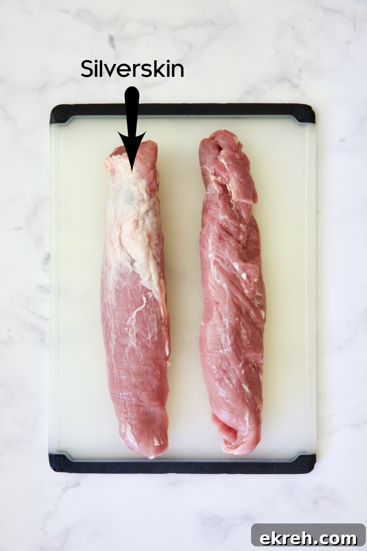 Grilled Citrus Mojo Pork Tenderloin Skewers 5 Two pork tenderloins on white plastic cutting board, one trimmed the other untrimmed.